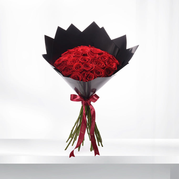 Vibrant red roses in sleek black wrap, tied with burgundy ribbon, elegant and romantic.