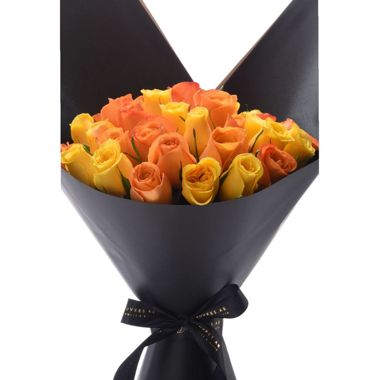 Vibrant yellow-orange roses in sleek black paper, tied with branded ribbon.