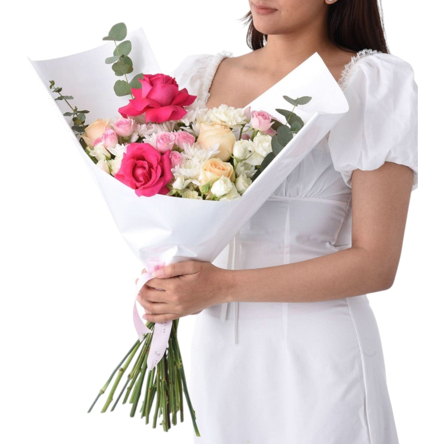 Woman in white dress holds vibrant pink, white, and peach rose bouquet wrapped in white paper.