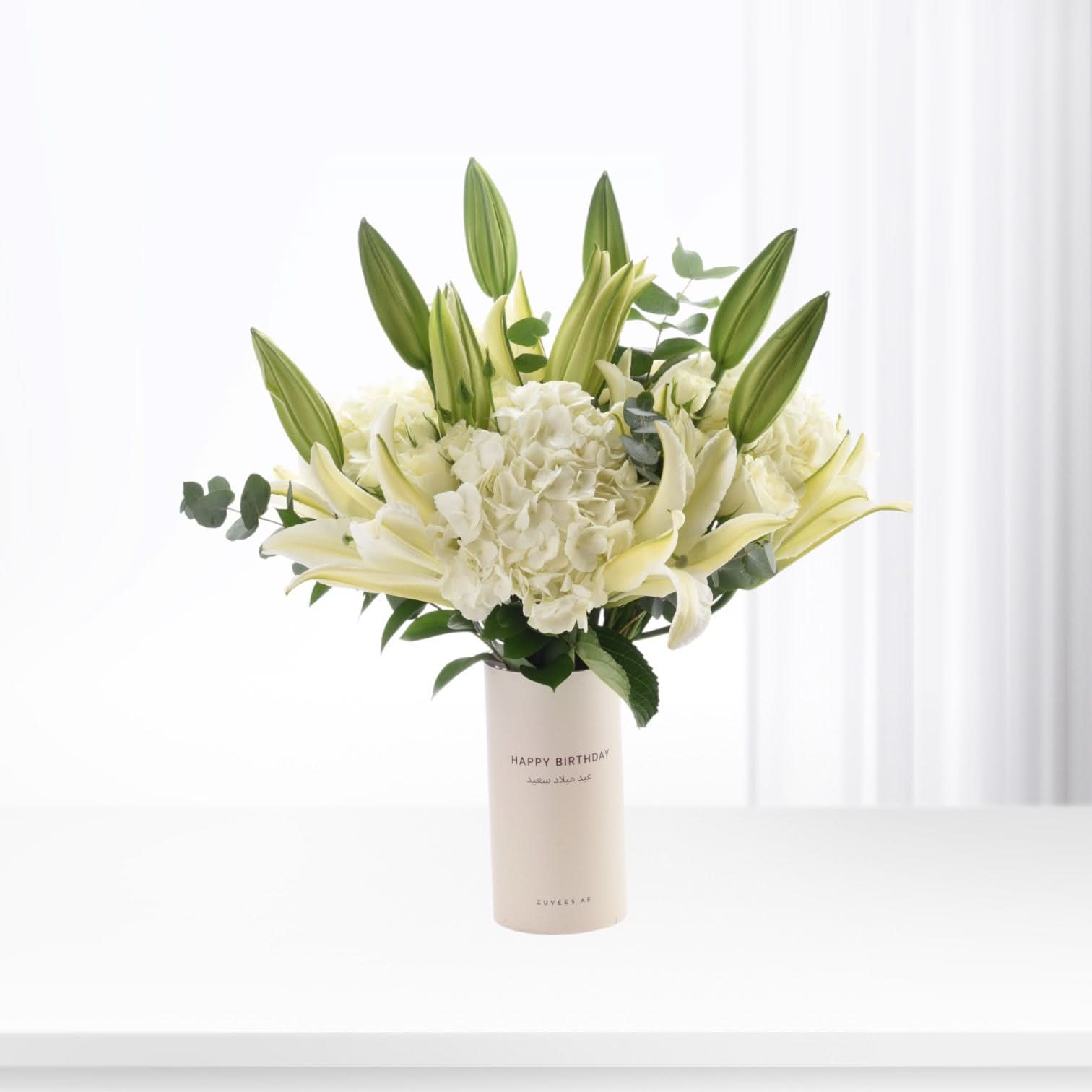 Elegant white lilies, hydrangeas, and buds in minimalist vase with "Happy Birthday" text.