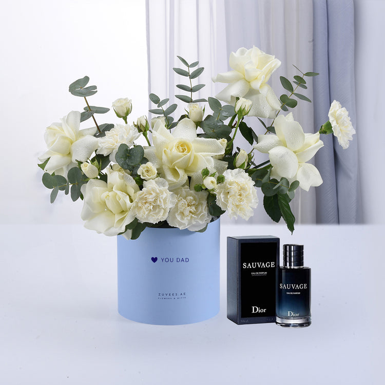White roses and eucalyptus in light blue “You Dad” vase beside Dior Sauvage perfume.