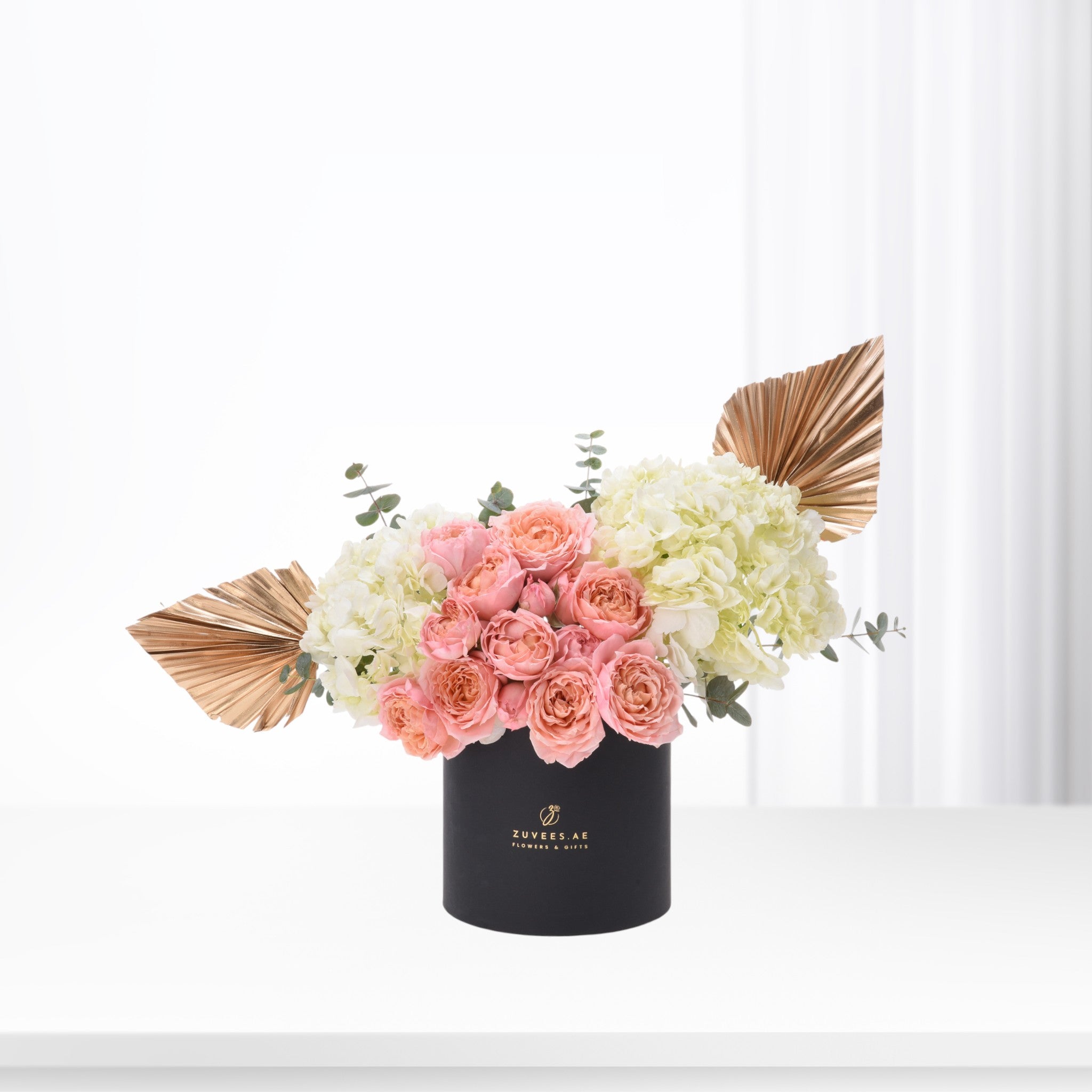 Elegant pink roses and white hydrangeas in black vase with gold accents.