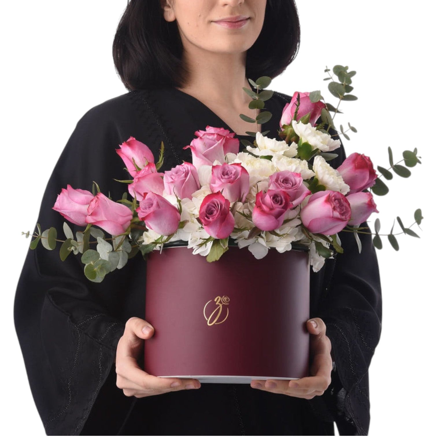 Woman holds burgundy hat box filled with pink roses and white blooms.