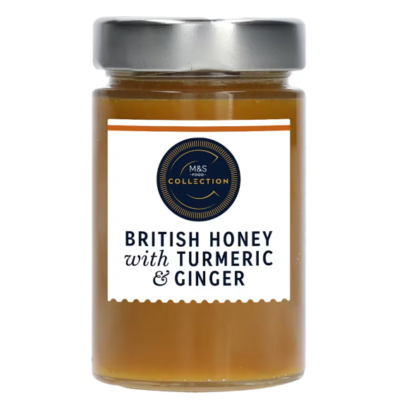 Clear glass jar of M&S British honey with turmeric & ginger, amber liquid, silver lid, navy label.