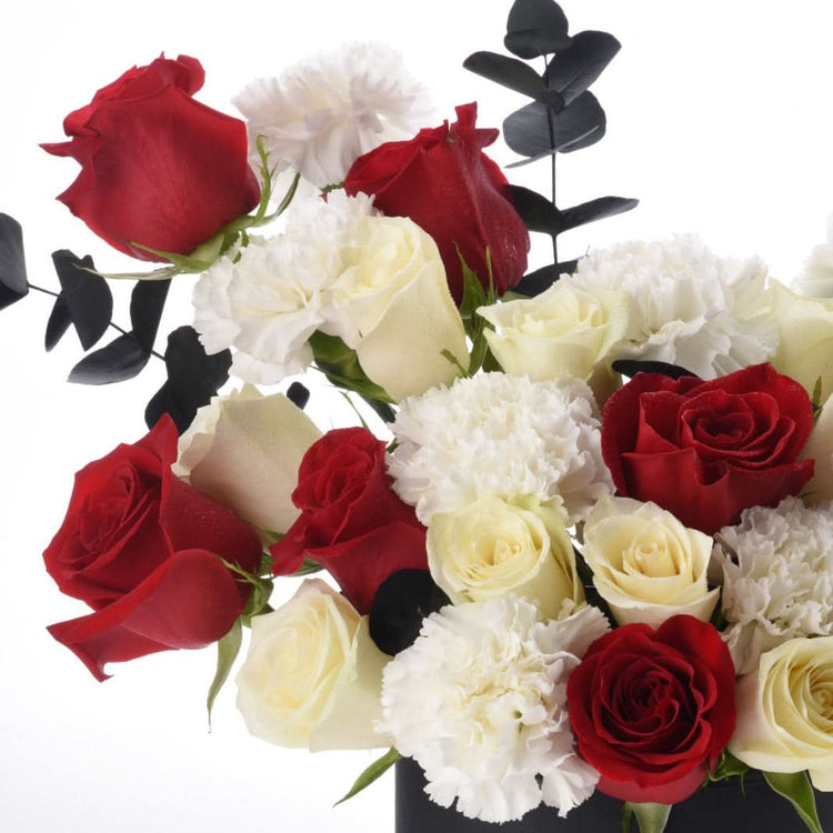 Elegant black box with red and white roses from, paired with fine chocolates of Zuvees Luxe Chocolate, Mirzam and Lakrids — a refined romantic gift.