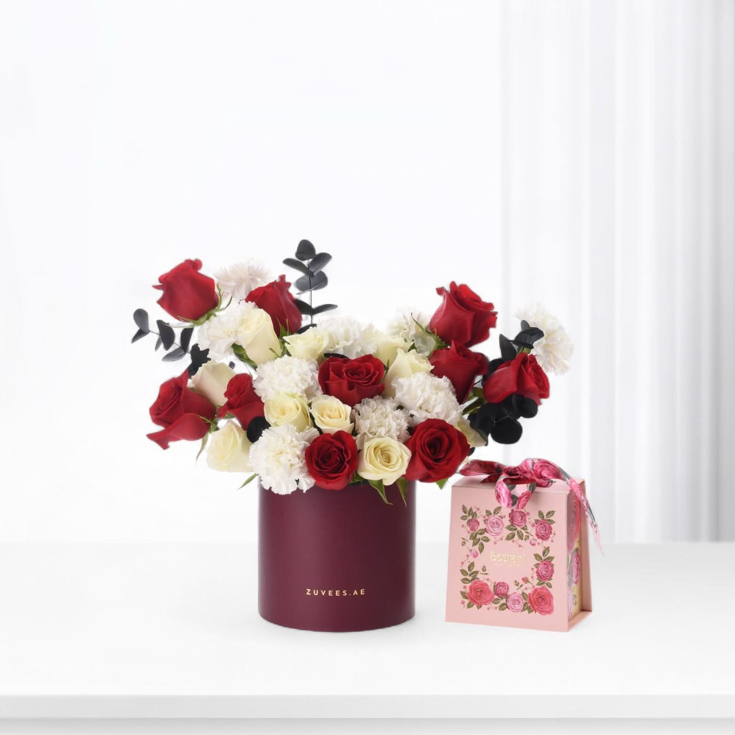 Elegant red and white rose bouquet in burgundy vase with floral gift box.