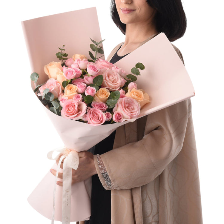 Soft pink and peach roses wrapped in matching paper, tied with elegant ribbon.