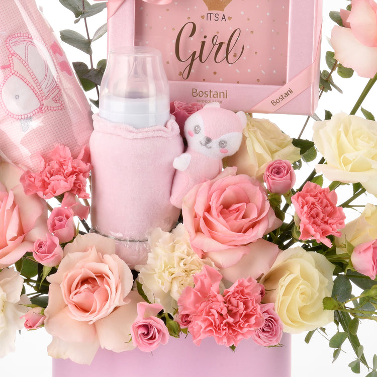 Pink baby shower bouquet with roses, plush toy, bottle, and chocolate gift.