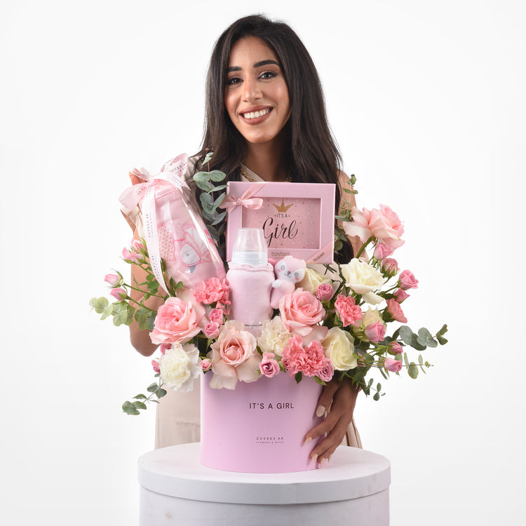 Pink floral baby shower gift basket with plush toys and framed “It’s a Girl” message.