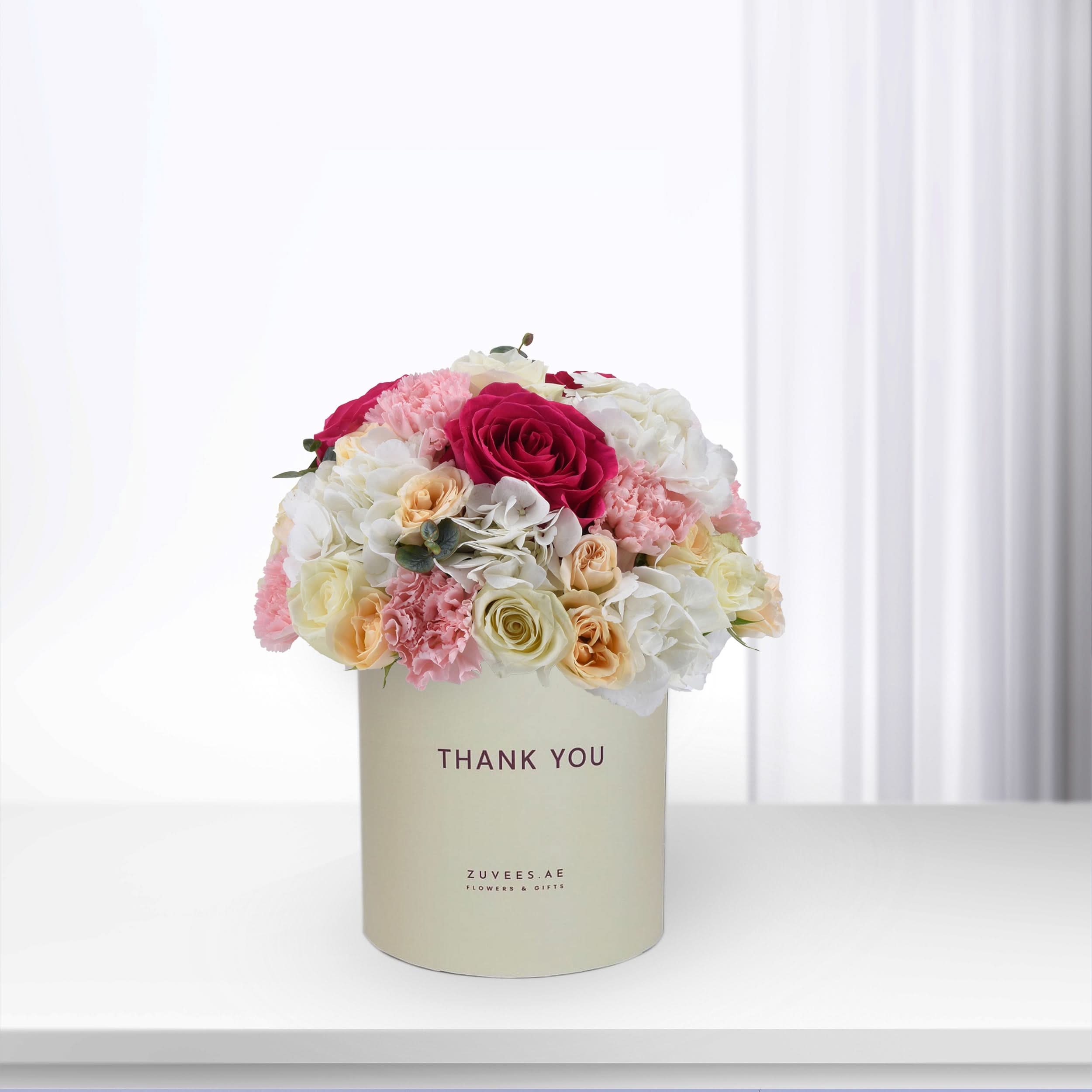 Cream box holds vibrant pink, white, and peach roses and carnations, "Thank You" printed.