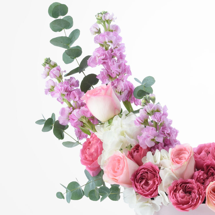Soft pink roses, lavender blooms, and eucalyptus create a delicate, romantic floral arrangement.