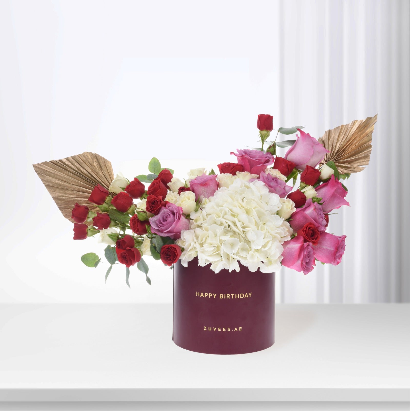 Luxury birthday bouquet: red, pink, white roses & hydrangeas in burgundy box with gold text.