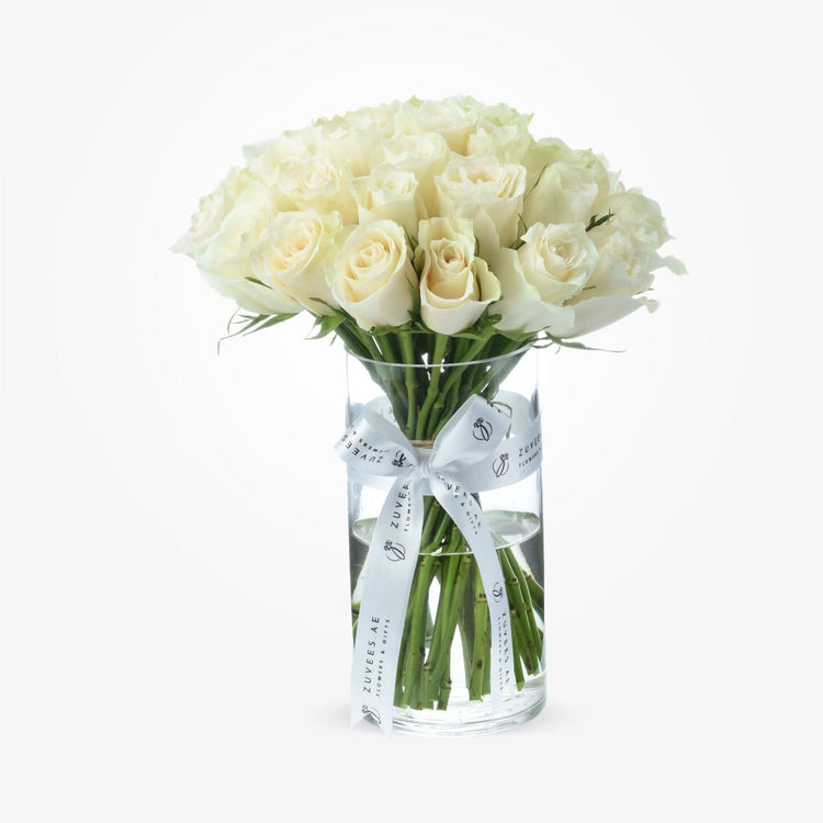 Elegant white roses in clear vase, tied with branded white ribbon.