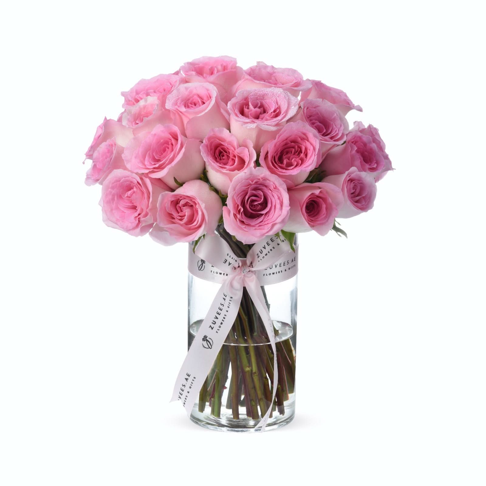 Pink roses in clear glass vase, elegantly tied with branded ribbon.