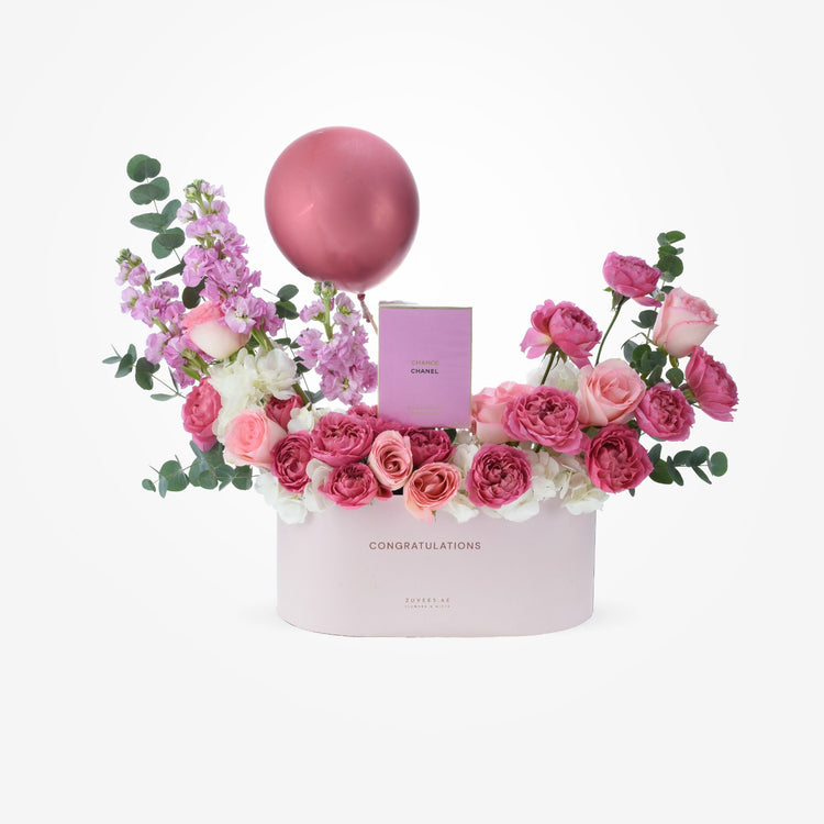 Pink floral arrangement with Chanel perfume and balloon in celebratory box.