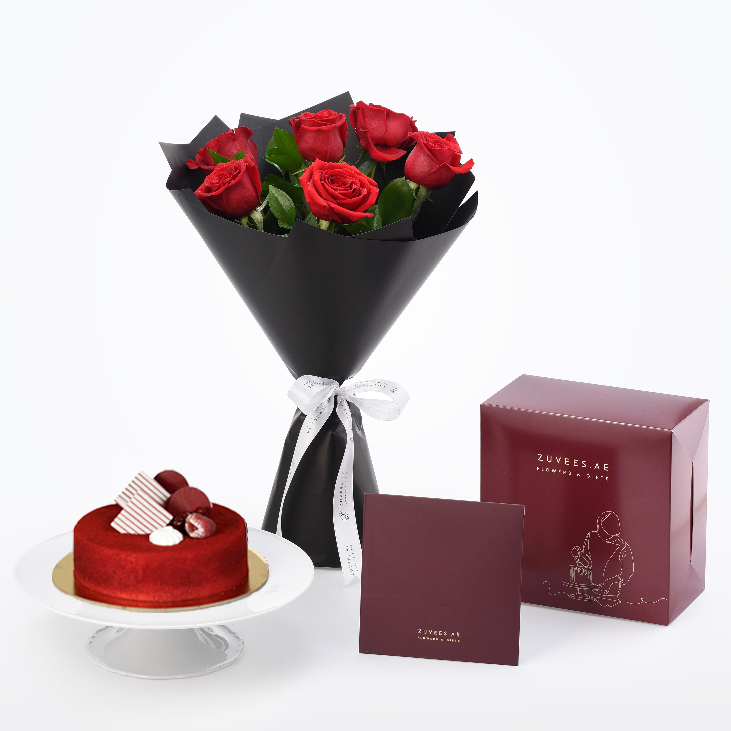 Vibrant red roses in black wrap, red velvet cake, burgundy gift boxes, elegant white ribbon.