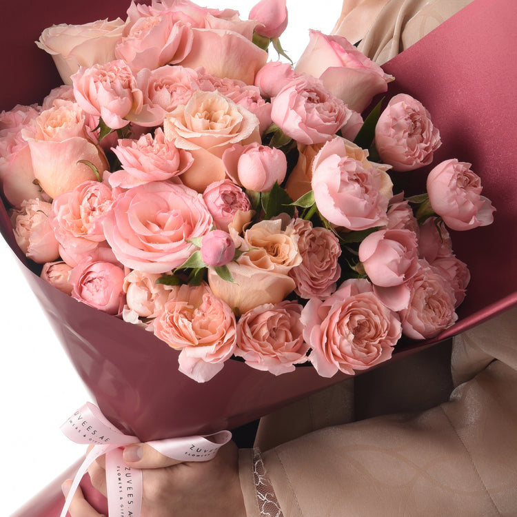 Luxurious pink rose bouquet with dewdrops, elegantly wrapped in satin, held gently for gifting.