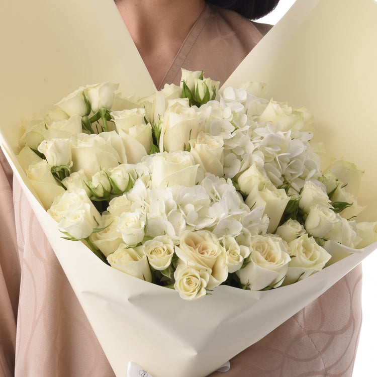 Elegant white rose and hydrangea bouquet wrapped in creamy paper.
