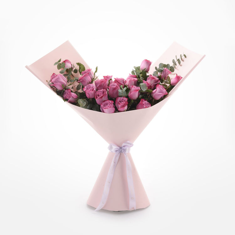 Pink roses in blush wrap with lavender ribbon, eucalyptus accents, elegant gift bouquet.