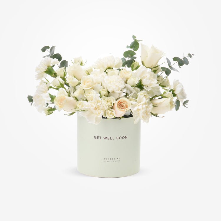 Soft white roses and eucalyptus in mint "Get Well Soon" cylinder.
