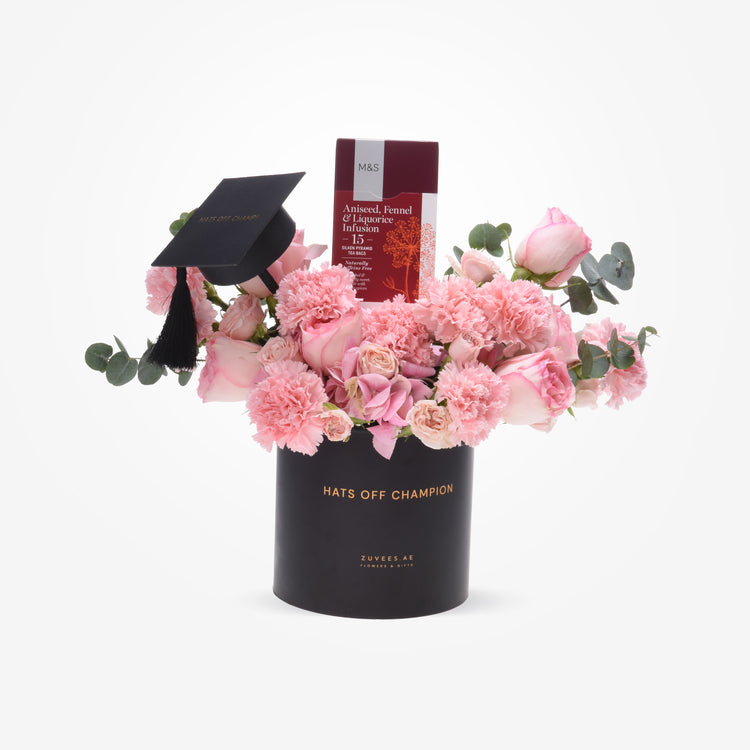 Black graduation cap atop pink roses and carnations in sleek black vase with "Hats Off Champion" text.