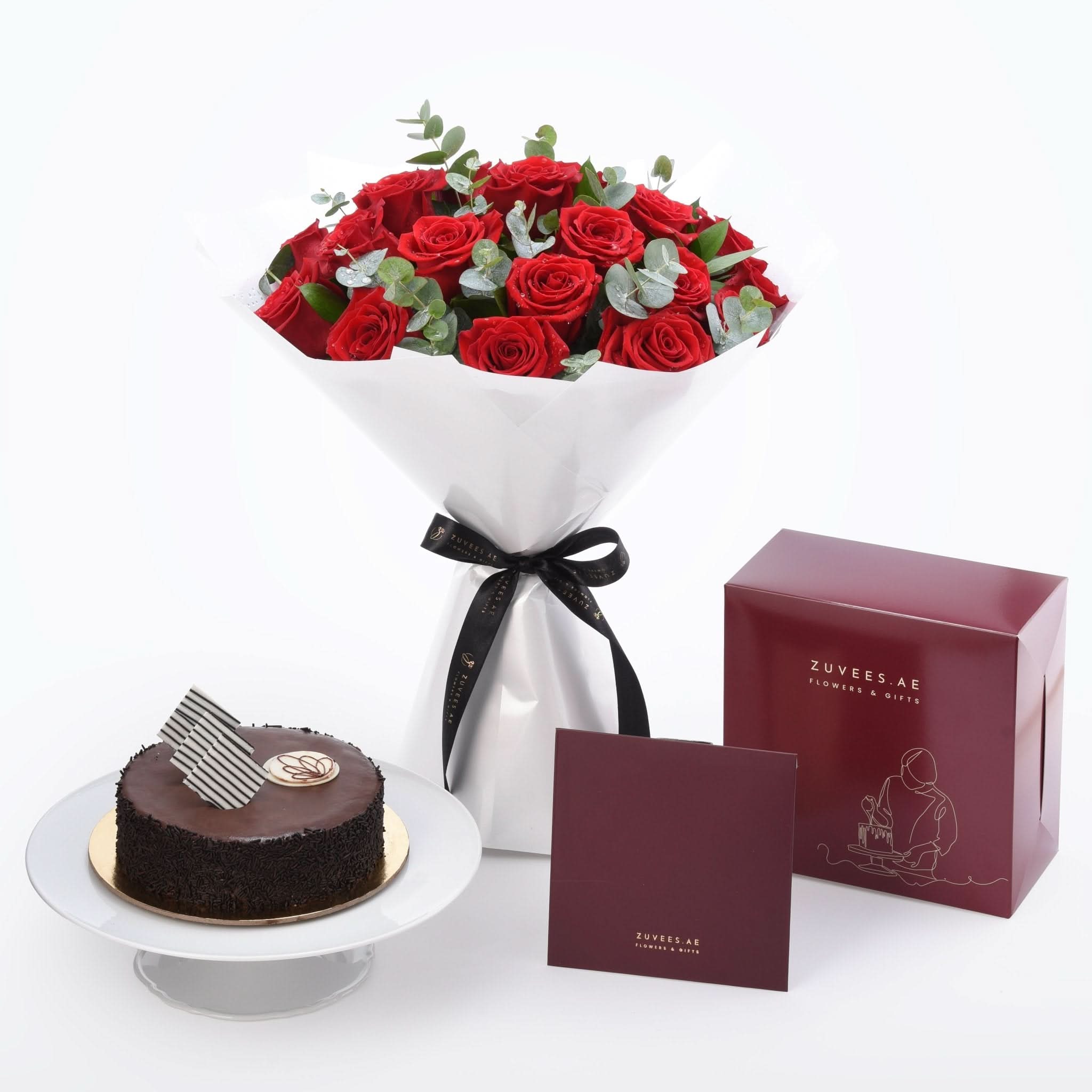 Vibrant red roses with eucalyptus, chocolate cake, and branded gift boxes.