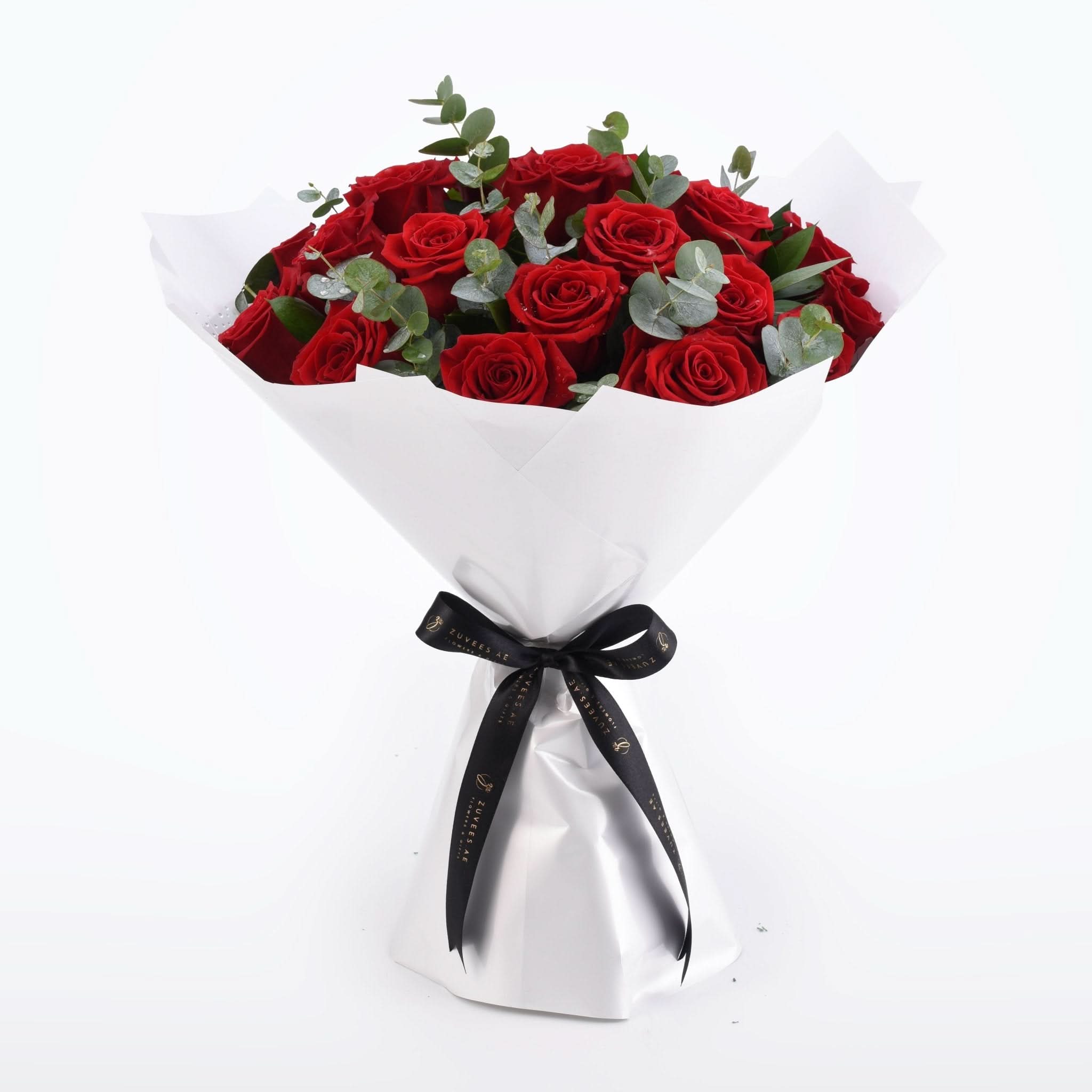 Vibrant red roses with eucalyptus, wrapped in white paper and black ribbon.