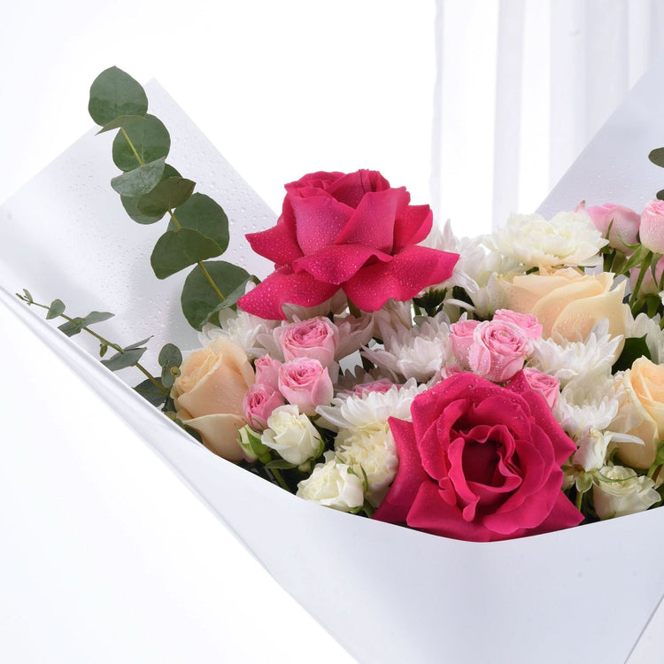 Vibrant pink, peach, and white roses with eucalyptus in dew-kissed white box bouquet.