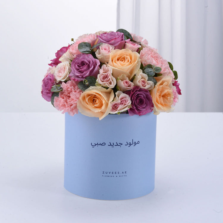 Pastel pink, purple, and peach roses in light blue box with Arabic birthday message.