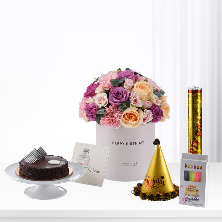 Pink, purple, and peach roses in white box with cake, hat, and candles.
