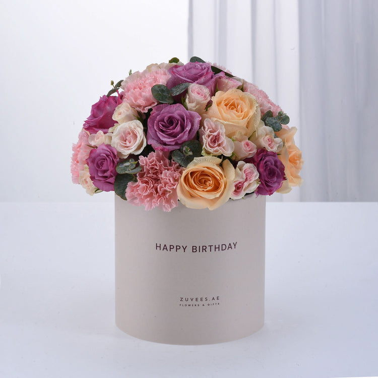 Pastel pink, purple, and peach roses with carnations in a "Happy Birthday" box.
