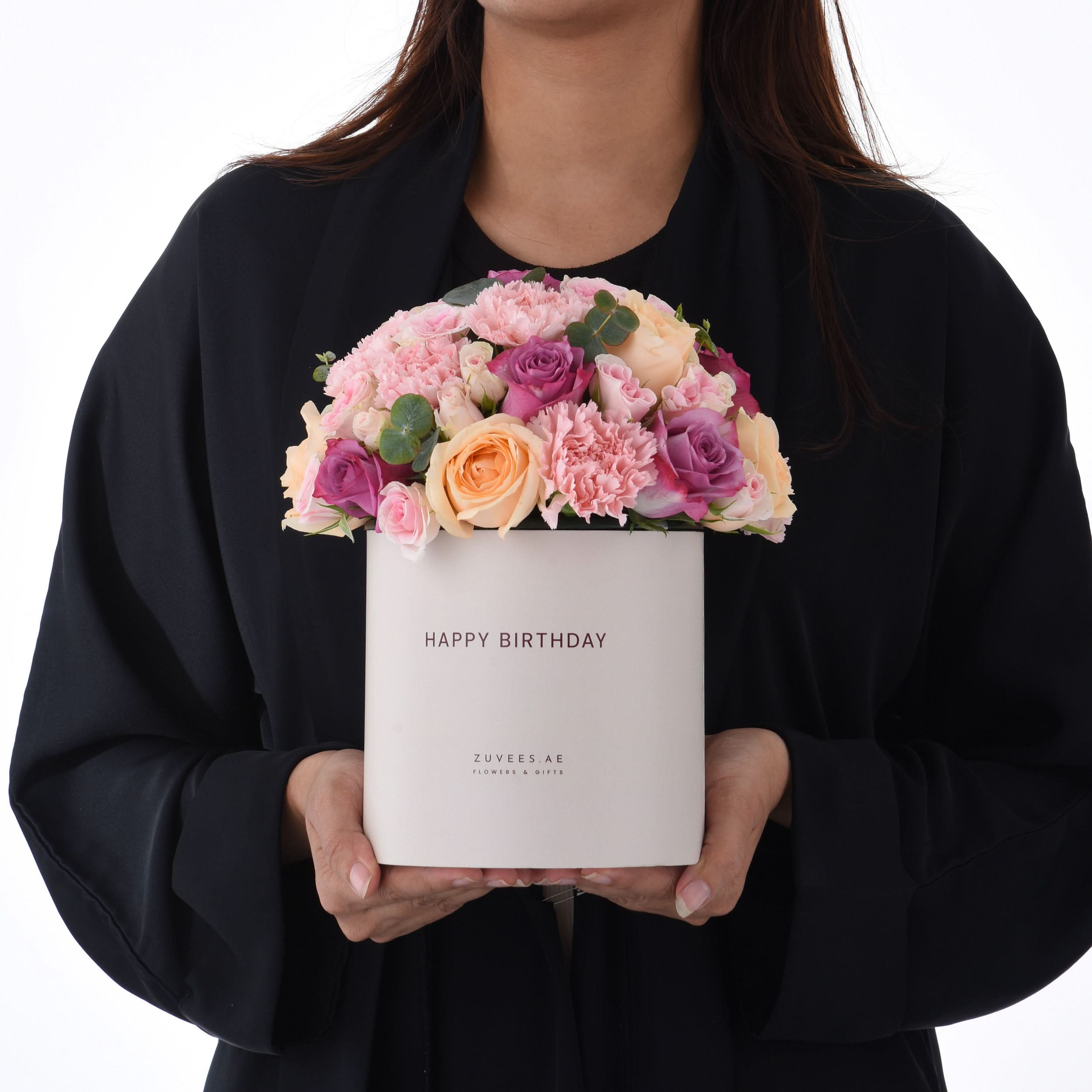 Elegant white box holds vibrant pink, purple, and peach roses for birthday celebration.