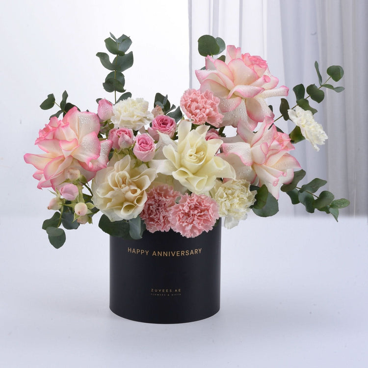 Elegant pink and cream roses with carnations in black “Happy Anniversary” vase.