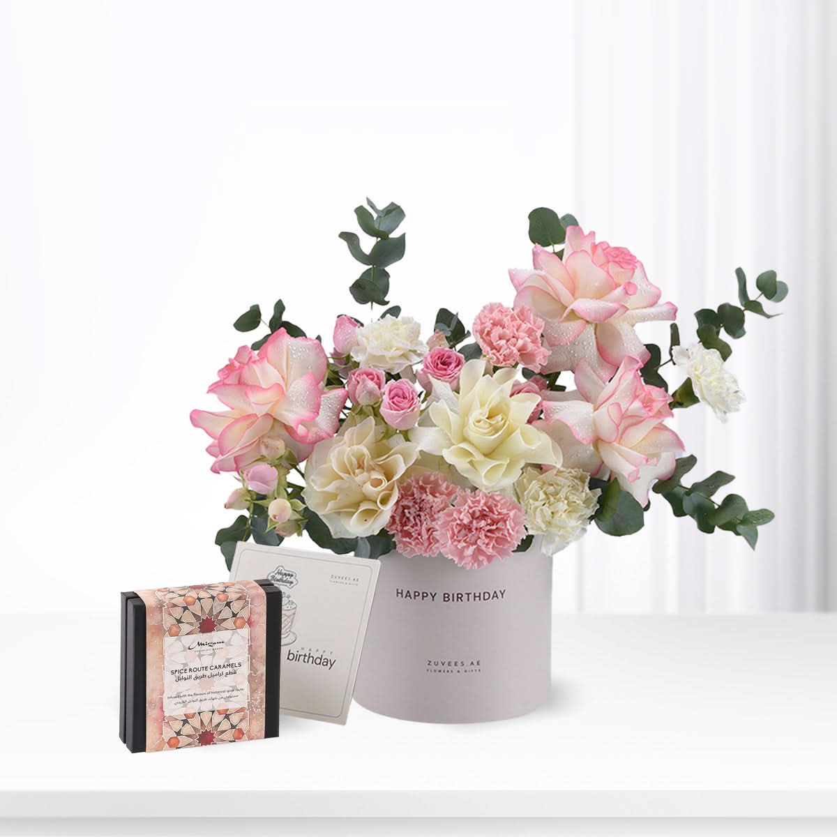 Soft pink roses, white carnations, and eucalyptus in lavender cylinder with "Happy Birthday" text.