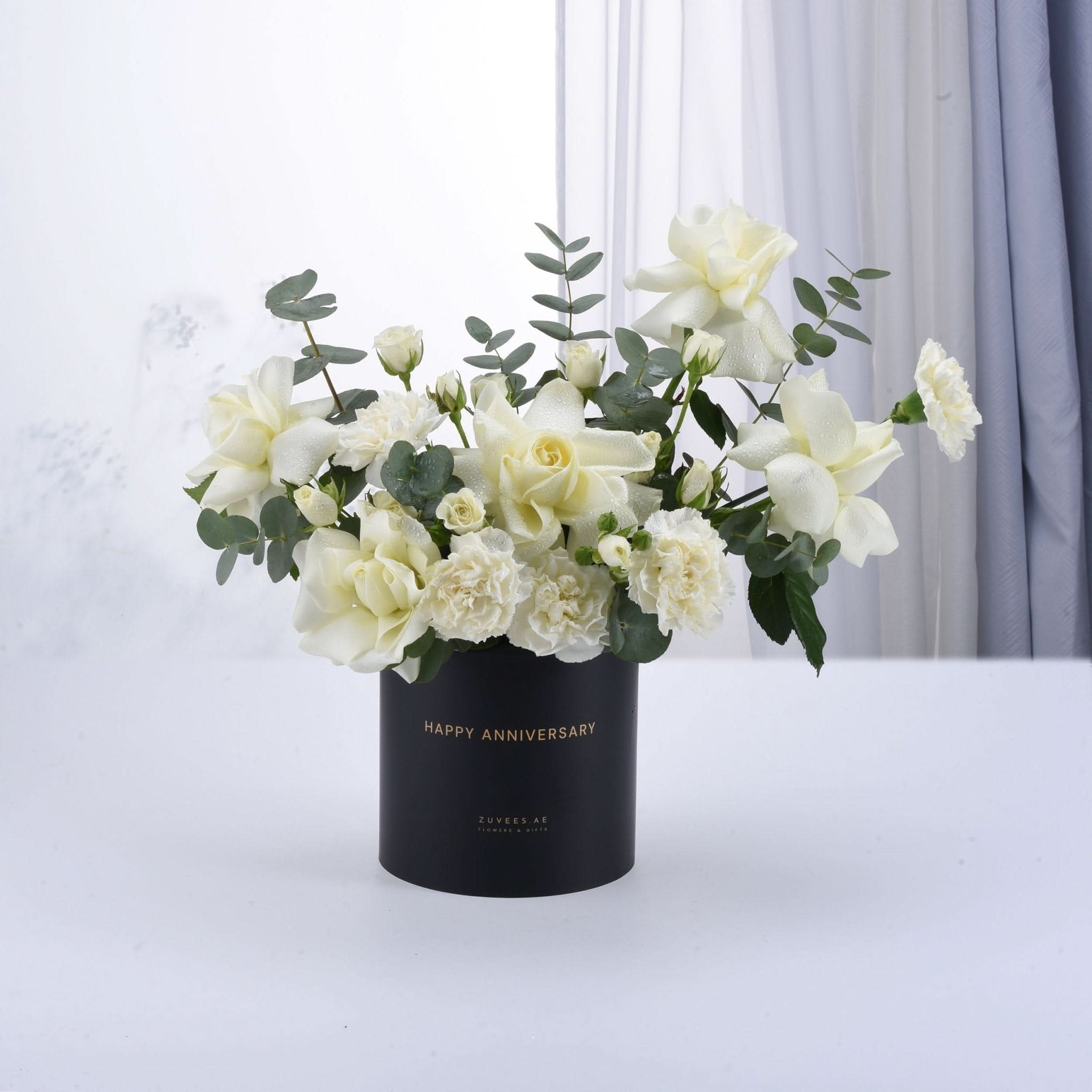 Elegant white roses and eucalyptus in matte black "Happy Anniversary" vase.