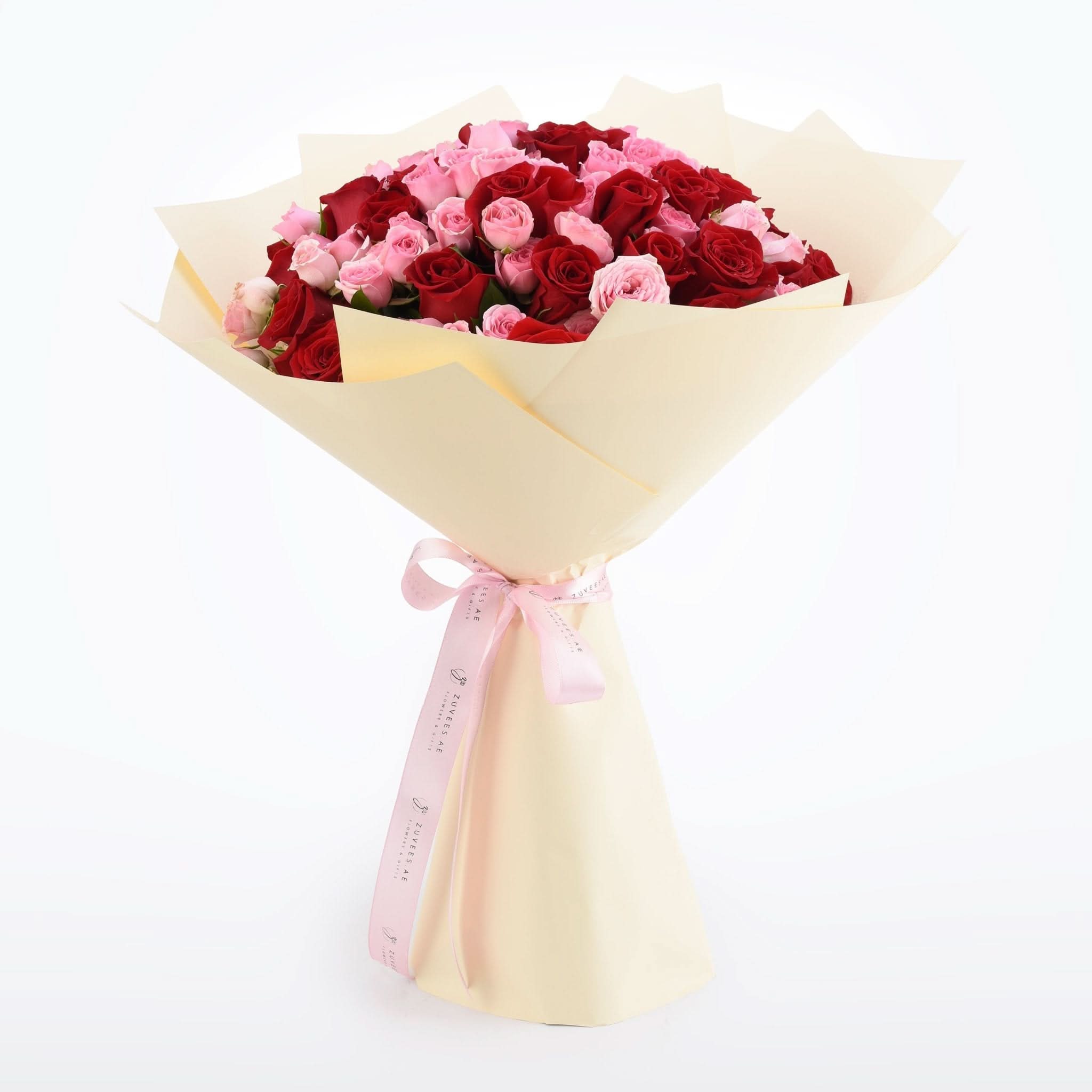 Vibrant red and pink roses wrapped in cream paper with pink ribbon.