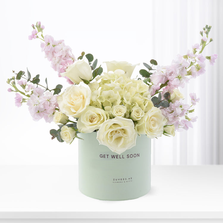 Pastel mint box holds creamy roses, lavender blooms, and eucalyptus—“Get Well Soon” message.