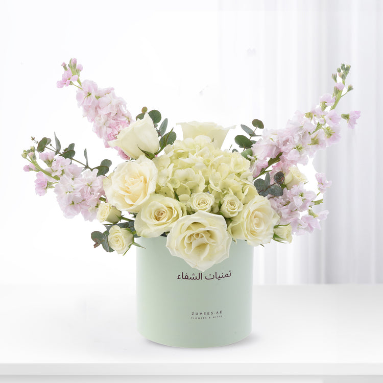 Elegant white roses, pink stock, and hydrangeas in mint green Zuvees box, soft light, luxury floral gift.