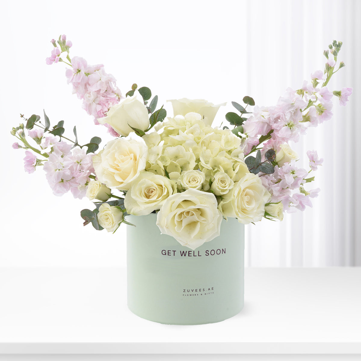 Pastel floral arrangement in mint "Get Well Soon" vase with roses and eucalyptus.