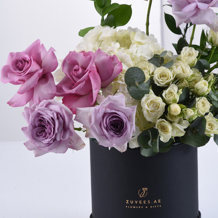 Elegant pink, purple, and white roses with hydrangeas in a sleek black Zuvees box.