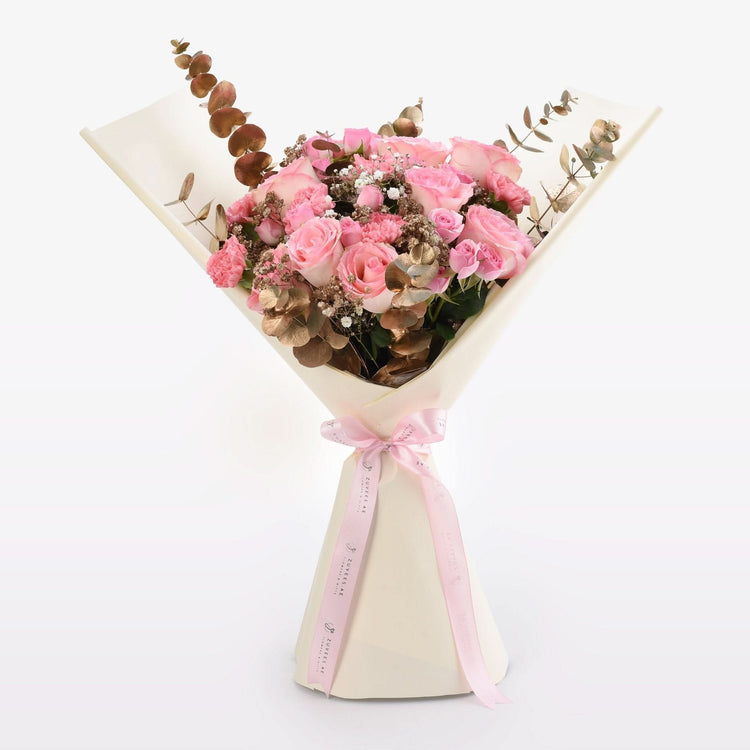 Soft pink roses, gold eucalyptus, and baby’s breath wrapped in cream paper with pink ribbon.