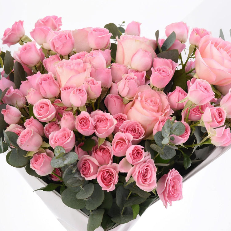 Abundant pink roses in white box, accented with lush green eucalyptus.
