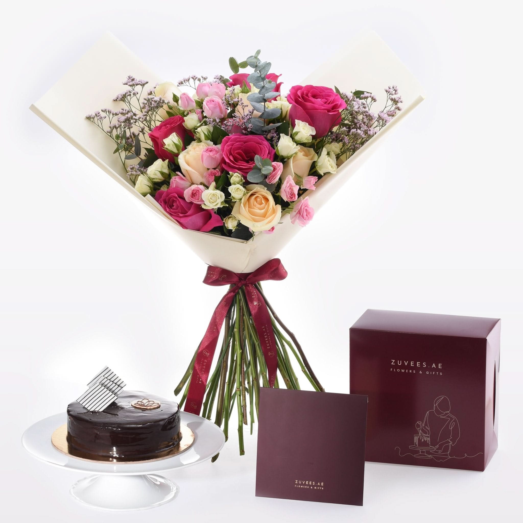 Vibrant pink, peach, and white roses with chocolate cake and branded gift box.