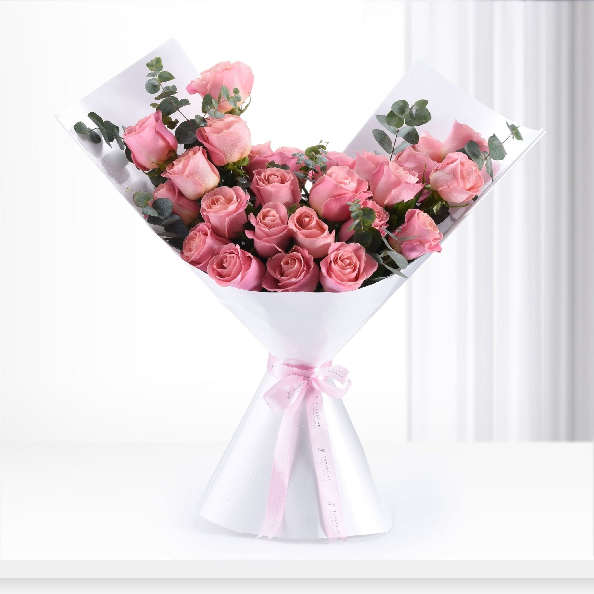 Soft pink roses with eucalyptus, wrapped in white paper and tied with a delicate pink ribbon.