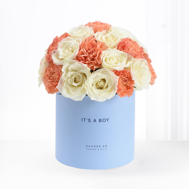 Pastel blue box holds creamy white roses and coral carnations, celebrating "It&