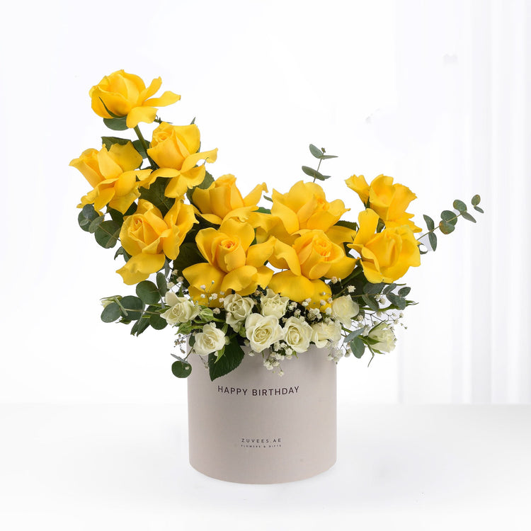 Vibrant yellow roses and white blooms in beige "Happy Birthday" cylinder vase.