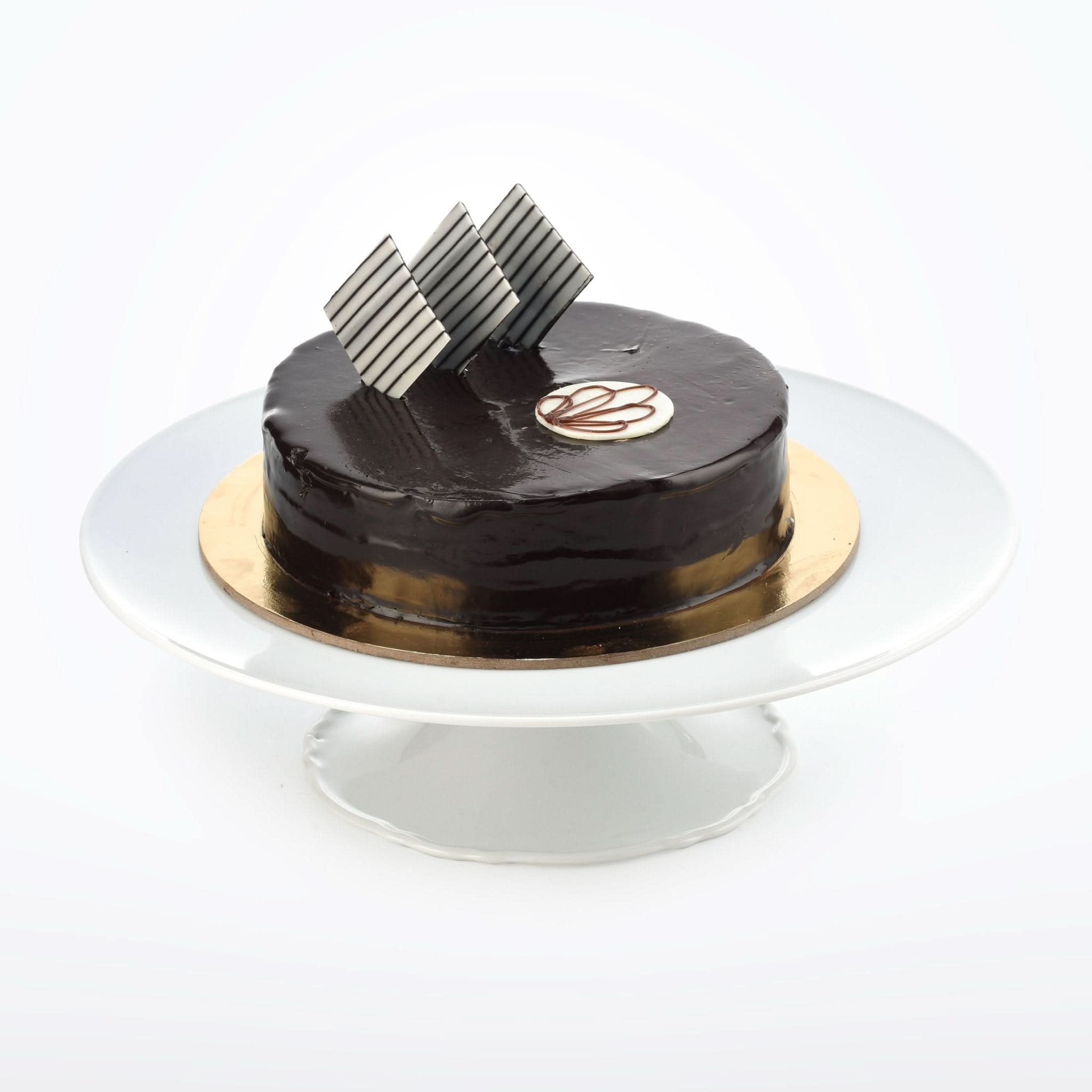 Glossy chocolate cake with striped shards, gold base, on white pedestal stand.
