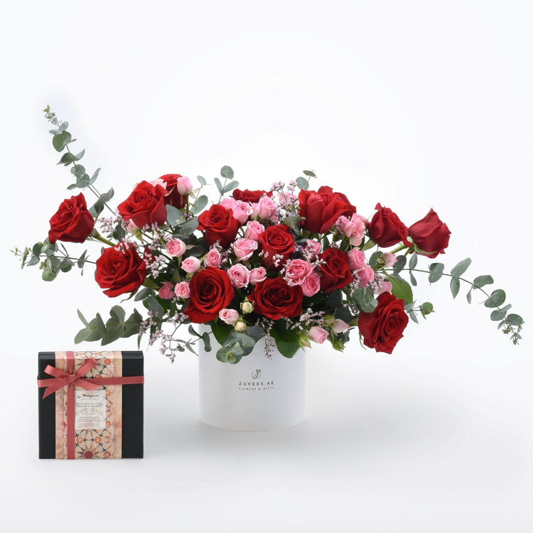 Vibrant red and pink roses with eucalyptus in white Zuvees box, paired with patterned gift box.