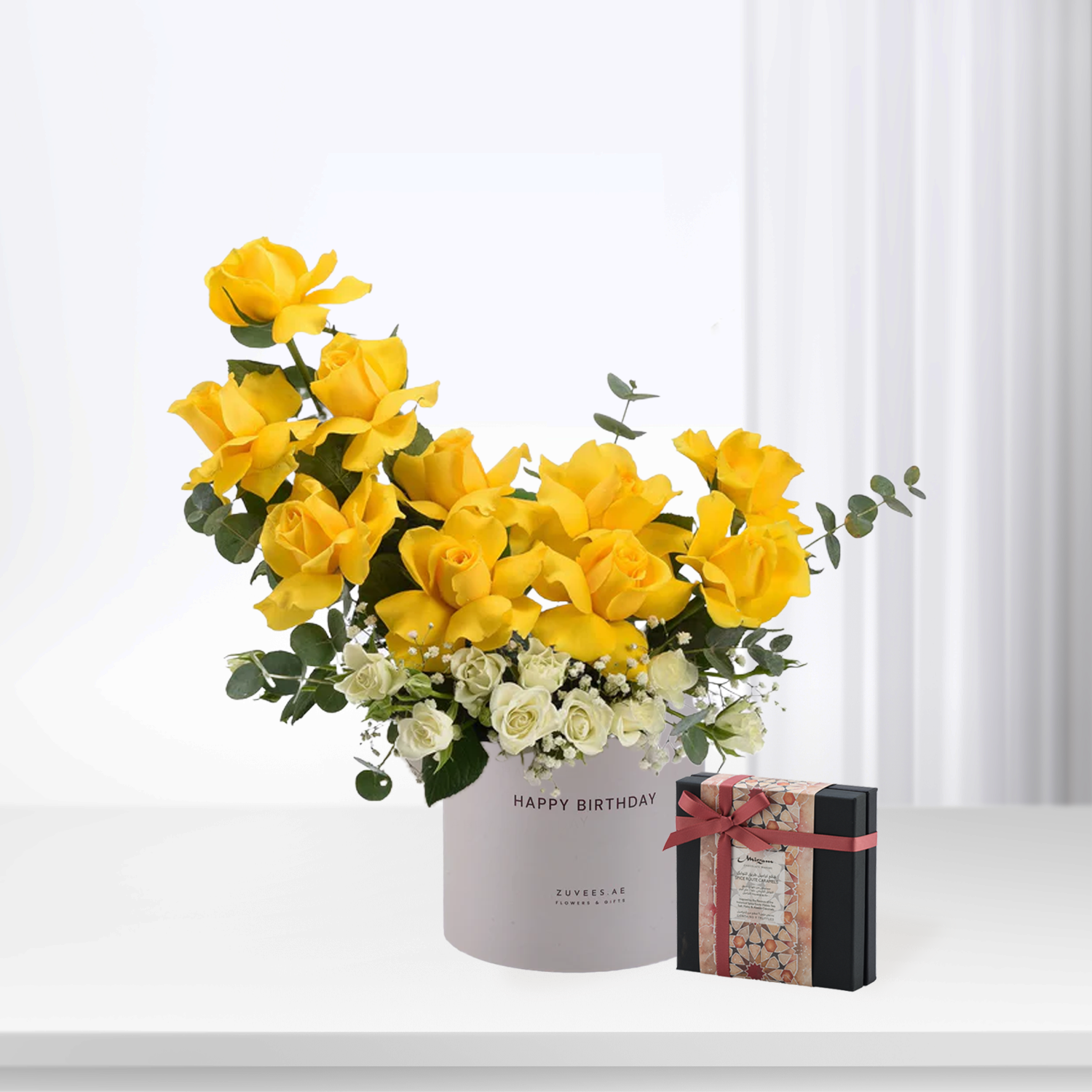 Vibrant yellow roses and white blooms in grey "Happy Birthday" box, beside patterned gift box.