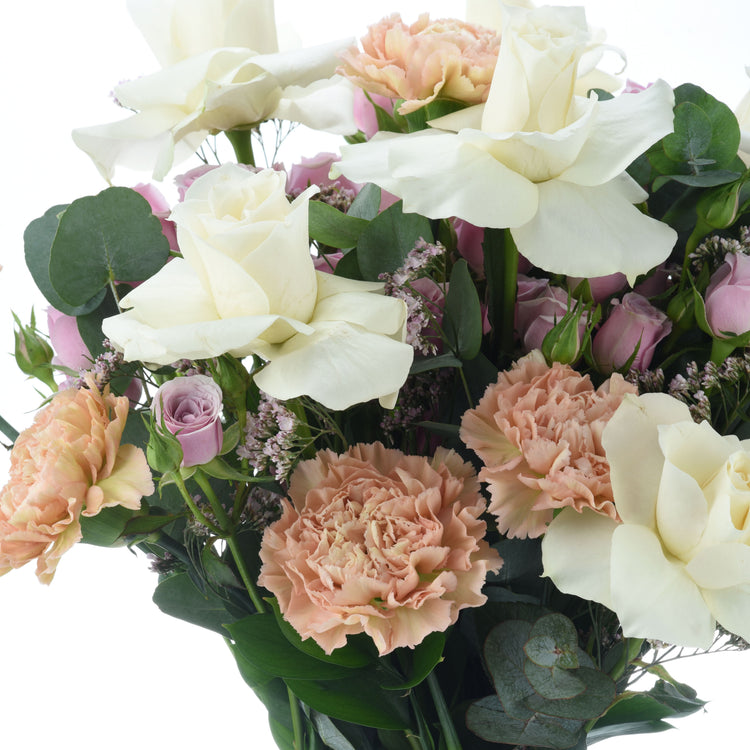 Elegant bouquet of creamy white roses, blush carnations, and pink roses with lush greenery.